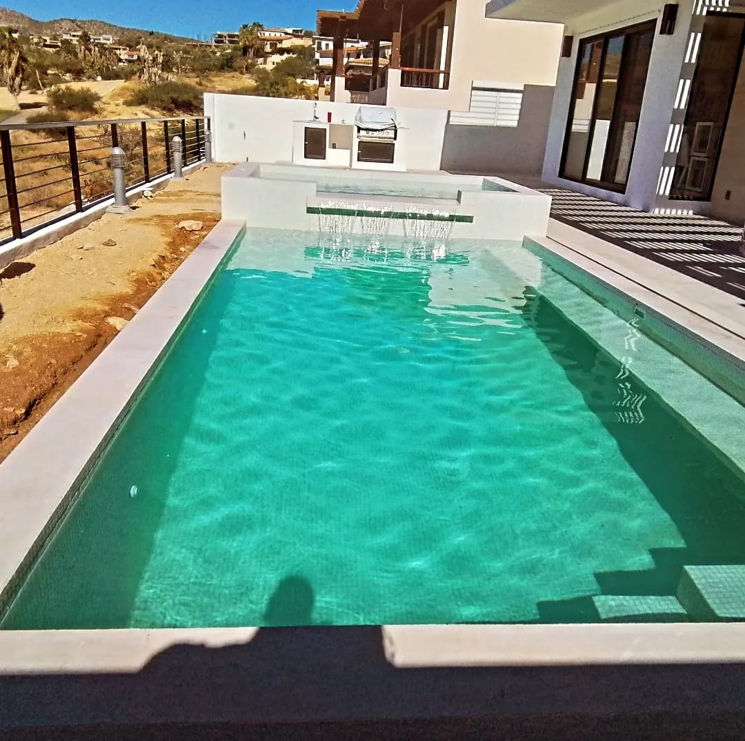 Alberca residencial junto a jardín y vivienda